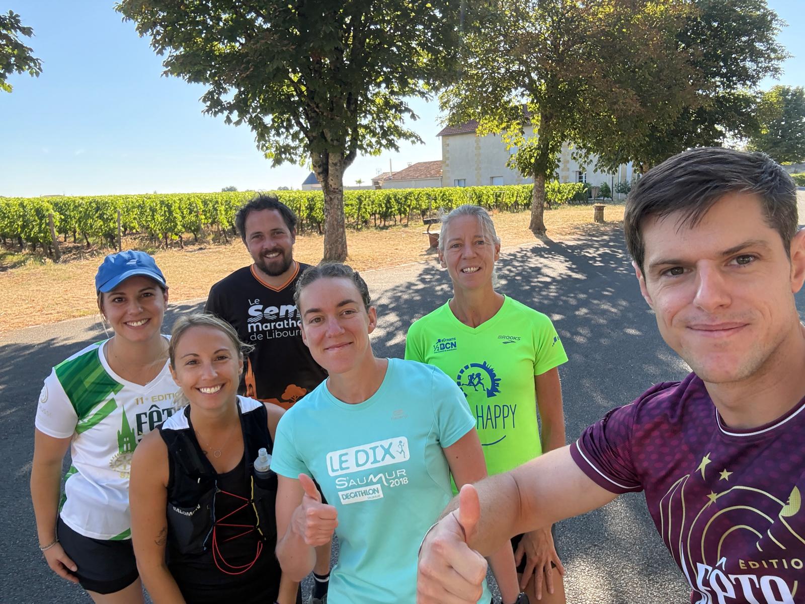 Six membres du club posent en souriant après une sortie, devant une rangée de vigne